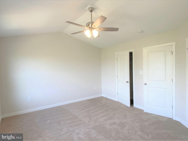 unfurnished bedroom with baseboards, a ceiling fan, vaulted ceiling, and light colored carpet