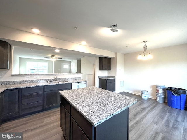 kitchen with a sink, a kitchen island, dark brown cabinets, and wood finished floors