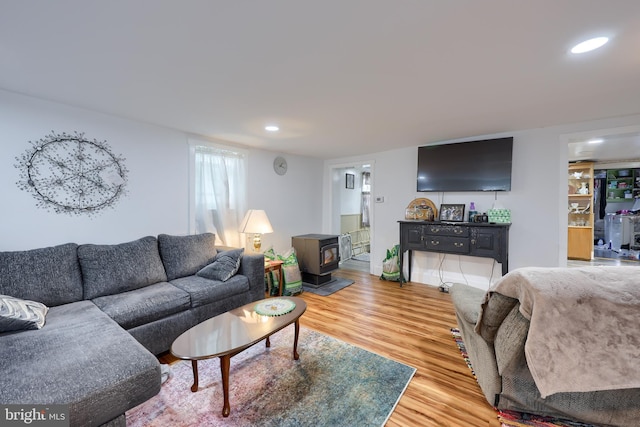 living area featuring light wood-type flooring, a wood stove, and recessed lighting