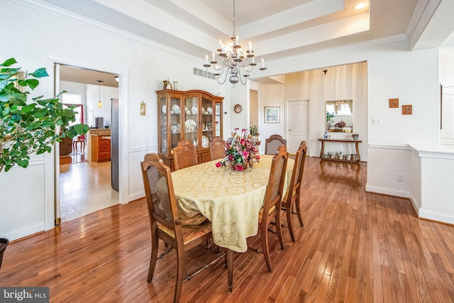 dining area with visible vents, baseboards, crown molding, wood finished floors, and a tray ceiling