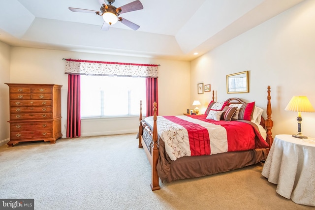 carpeted bedroom featuring ceiling fan, baseboards, and a tray ceiling