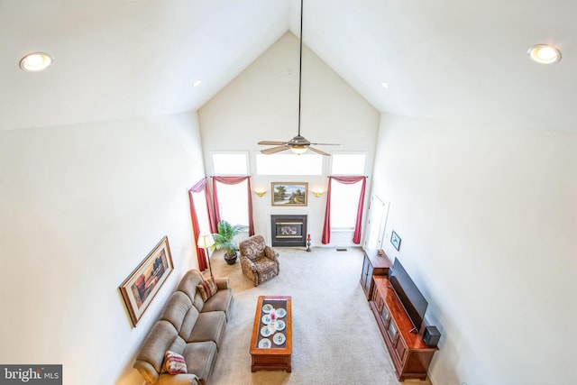 living area with carpet flooring, high vaulted ceiling, a glass covered fireplace, and recessed lighting