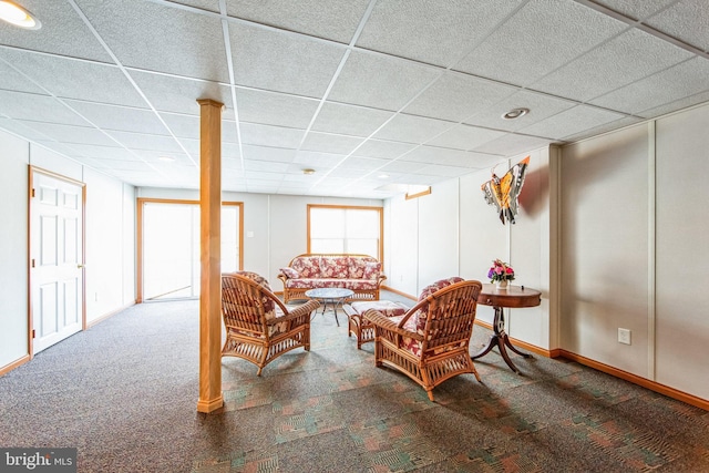 carpeted living room featuring a paneled ceiling and baseboards