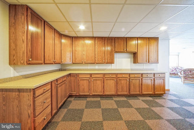 kitchen featuring light countertops, recessed lighting, a drop ceiling, and brown cabinetry