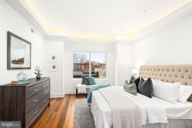 bedroom featuring dark wood-style floors, baseboards, a raised ceiling, visible vents, and recessed lighting