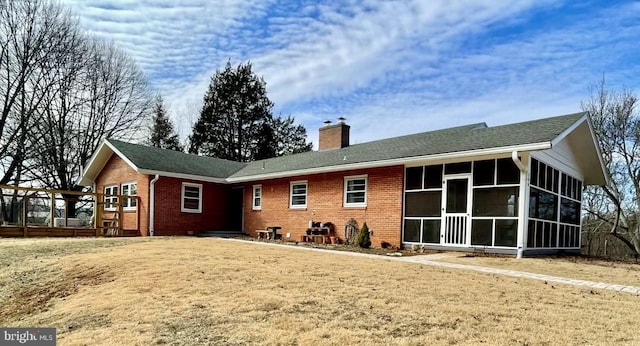 back of house featuring a sunroom, brick siding, and a chimney