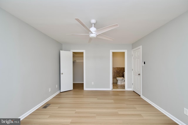 unfurnished bedroom featuring light wood-style flooring, visible vents, baseboards, a spacious closet, and ensuite bath