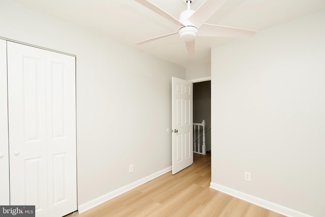 unfurnished bedroom with light wood-style floors, a closet, baseboards, and a ceiling fan