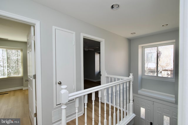 hallway with recessed lighting, visible vents, baseboards, an upstairs landing, and light wood-style floors