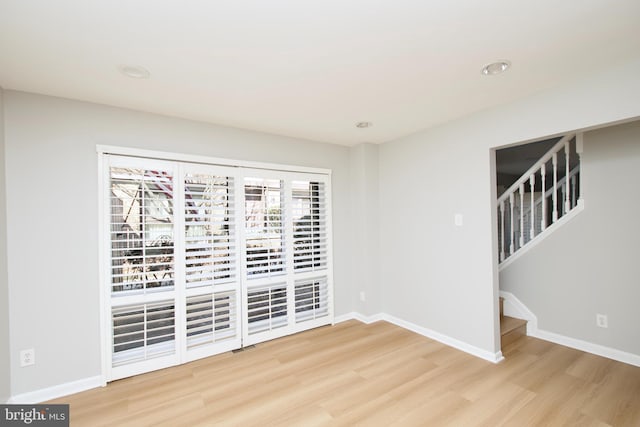 empty room with stairs, baseboards, and wood finished floors