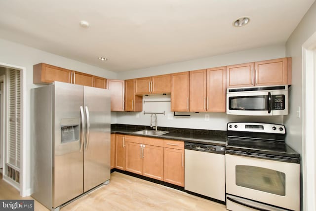 kitchen featuring stainless steel appliances, dark countertops, and a sink