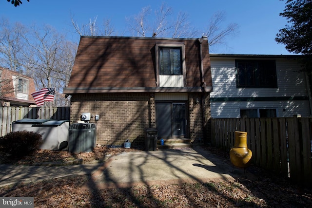 rear view of house featuring brick siding, central air condition unit, entry steps, a patio area, and fence