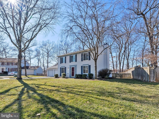 colonial inspired home with a garage, a chimney, fence, and a front yard