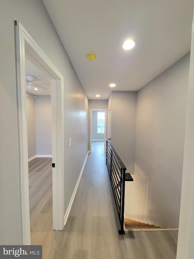 hall with recessed lighting, baseboards, an upstairs landing, and wood finished floors