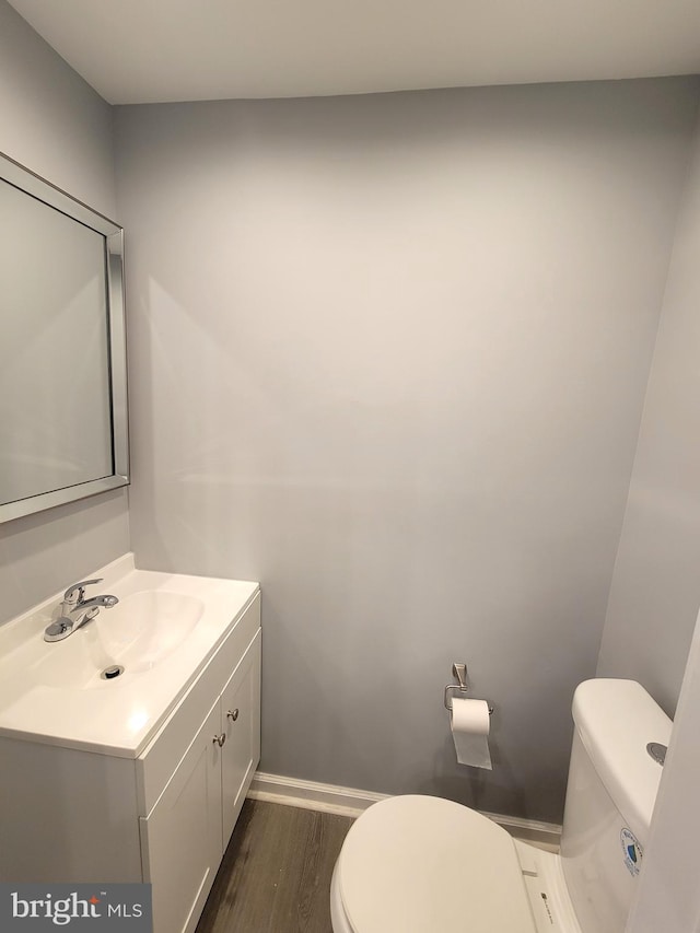 bathroom featuring wood finished floors, vanity, toilet, and baseboards