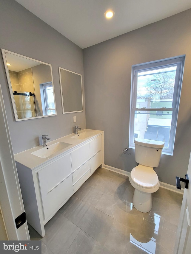 bathroom with toilet, a shower stall, baseboards, and a sink