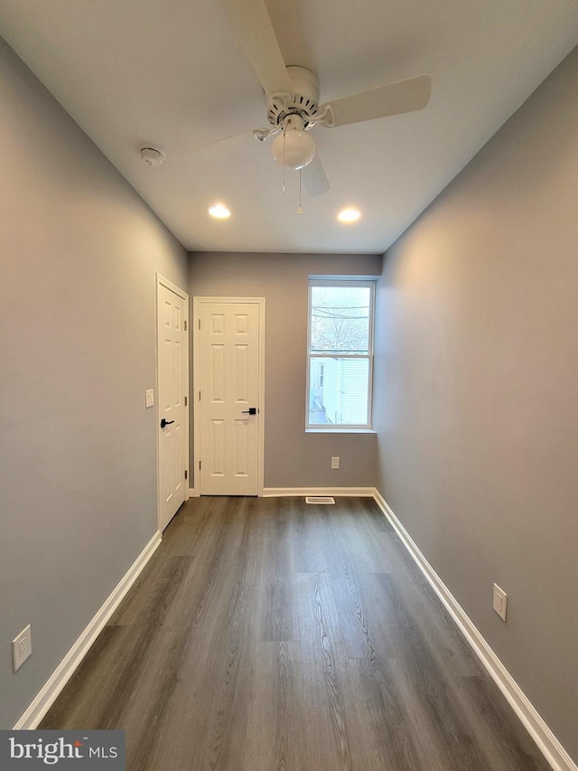 interior space featuring dark wood-type flooring, a ceiling fan, and baseboards