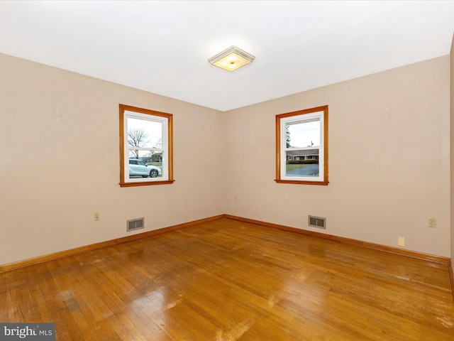 spare room featuring baseboards, visible vents, and light wood-style floors