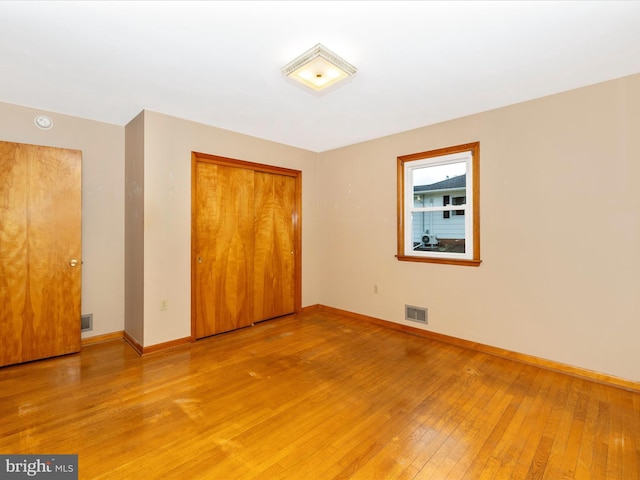 unfurnished bedroom with light wood finished floors, a closet, visible vents, and baseboards