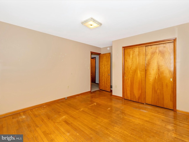 unfurnished bedroom with a closet, light wood-style flooring, and baseboards