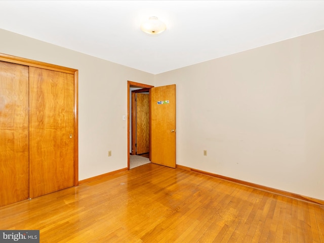 unfurnished bedroom featuring a closet, baseboards, and light wood finished floors