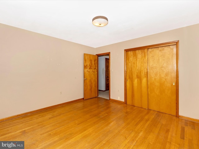 unfurnished bedroom featuring light wood-type flooring, baseboards, and a closet