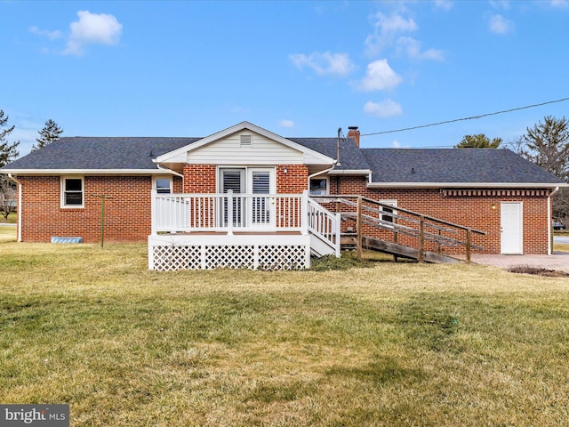 view of front of home with brick siding, a front lawn, a chimney, and a wooden deck