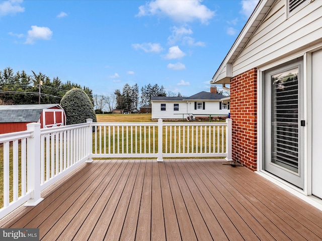 wooden deck featuring a storage unit, a lawn, and an outdoor structure