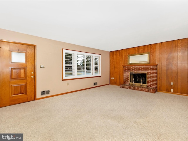 unfurnished living room featuring light carpet, visible vents, a fireplace, and wooden walls