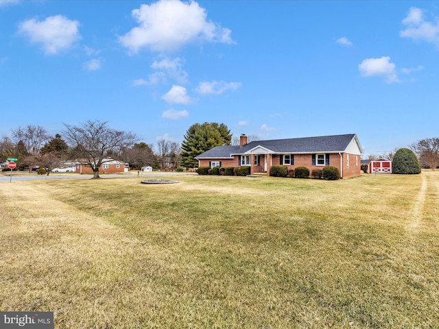 view of front facade with brick siding, a chimney, and a front lawn