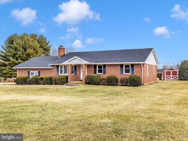 single story home featuring a shed, a chimney, a front yard, and brick siding