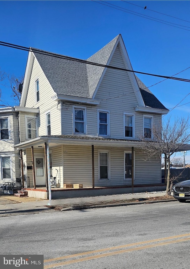 townhome / multi-family property featuring a porch and a shingled roof