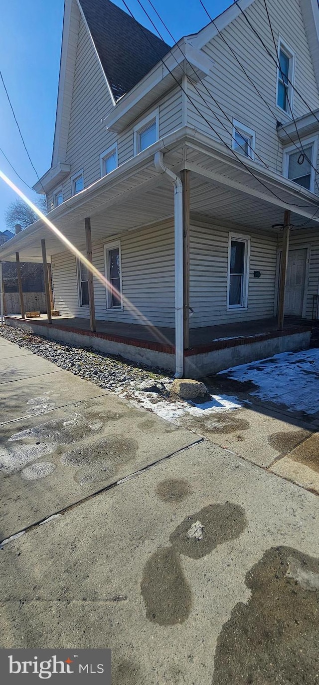 view of side of property featuring a porch and a shingled roof