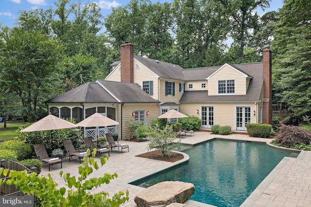 outdoor pool with french doors and a patio