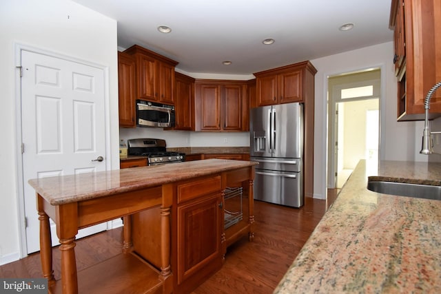 kitchen featuring a sink, stainless steel appliances, light stone countertops, and dark wood-type flooring