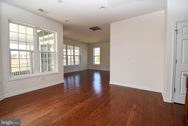 unfurnished room featuring visible vents, baseboards, and dark wood-style flooring