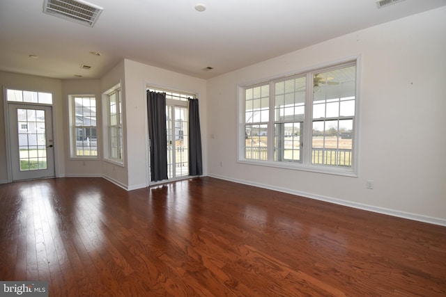 unfurnished room with dark wood-type flooring, visible vents, and baseboards