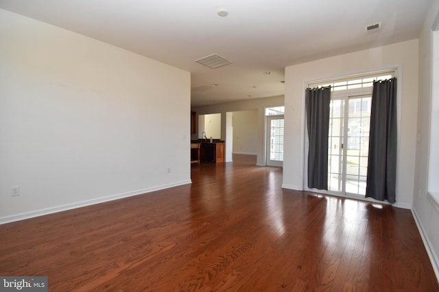 unfurnished room featuring a sink, visible vents, baseboards, and dark wood-type flooring