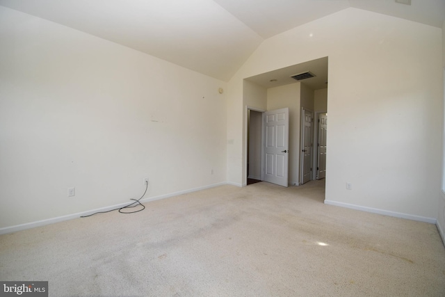 spare room with visible vents, lofted ceiling, light colored carpet, and baseboards