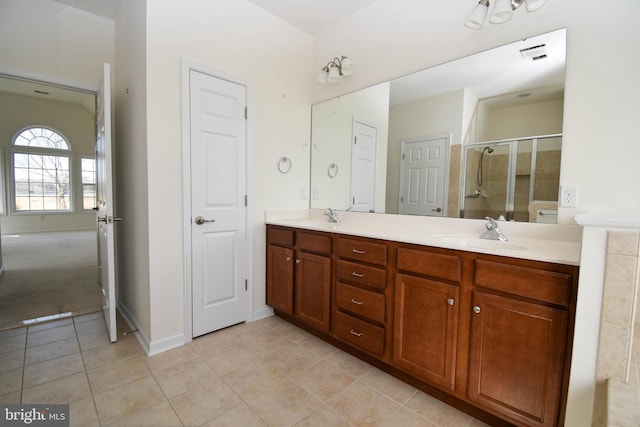 bathroom with a sink, a stall shower, double vanity, and tile patterned floors