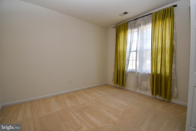 spare room featuring visible vents, light colored carpet, and baseboards