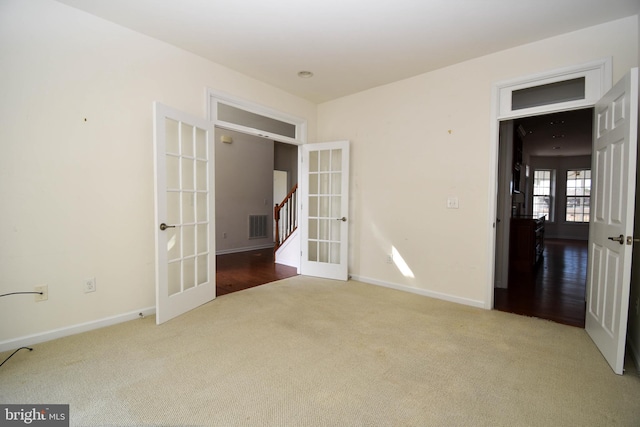 carpeted spare room with stairs, french doors, visible vents, and baseboards