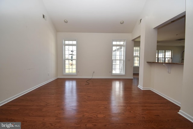 spare room featuring visible vents, baseboards, and dark wood-style floors