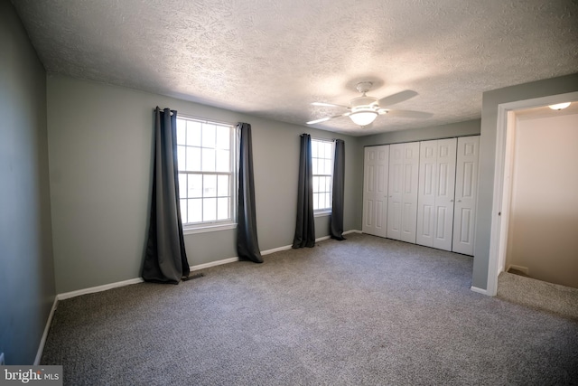 unfurnished bedroom with a textured ceiling, a ceiling fan, baseboards, a closet, and carpet