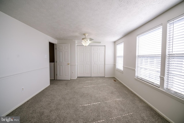 unfurnished bedroom featuring carpet, a closet, ceiling fan, a textured ceiling, and baseboards