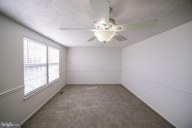 empty room with a textured ceiling, carpet flooring, a ceiling fan, and baseboards