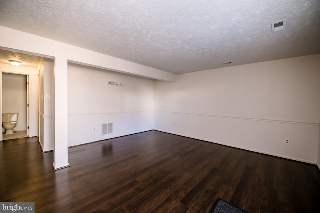 spare room with a textured ceiling, visible vents, and wood finished floors