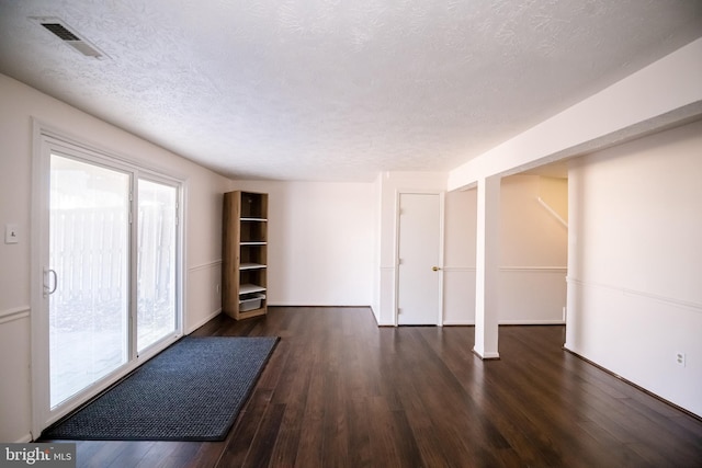 unfurnished living room featuring a textured ceiling, visible vents, and wood finished floors