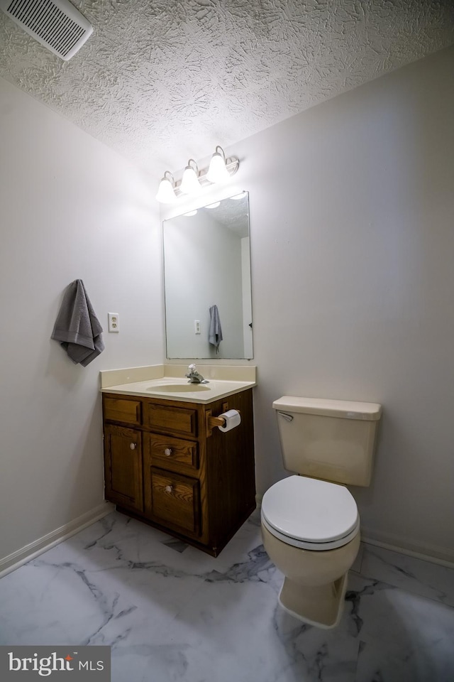 bathroom featuring a textured ceiling, toilet, vanity, visible vents, and marble finish floor