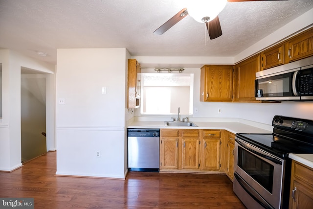 kitchen with dark wood-style flooring, stainless steel appliances, a textured ceiling, light countertops, and a sink